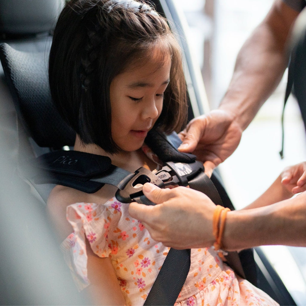 Person securing a child in a car seat with a focus on safety.